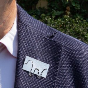 Refraction-extended wave brooch worn on mans lapel