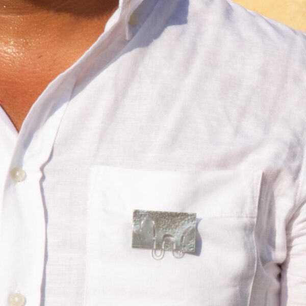 Refraction-extended wave brooch worn on mans shirt pocket